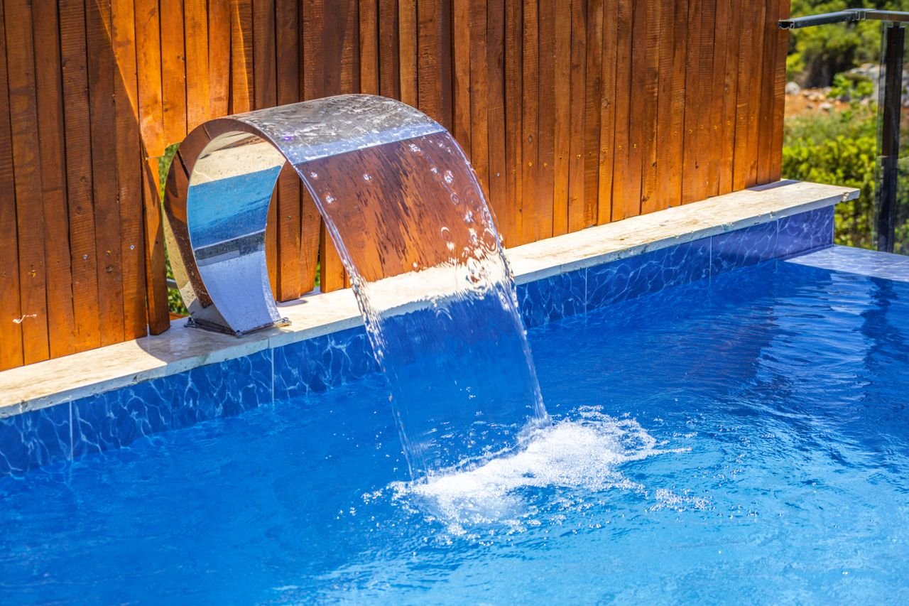 Elegant swimming pool with a sleek stainless steel waterfall at a resort.